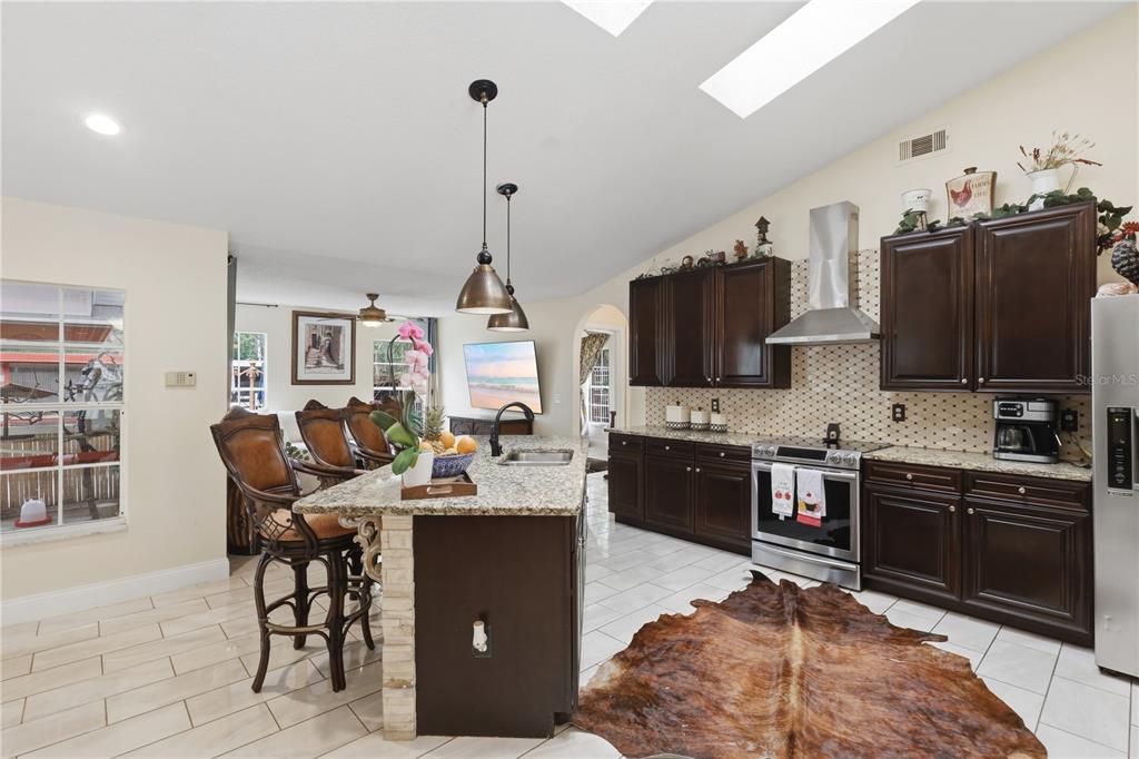 1898 Blackwelder Road De Leon Springs, FL 32130 - Photo 5 of 33 a kitchen with stainless steel appliances kitchen island granite countertop a sink dishwasher a stove and a refrigerator with wooden floor