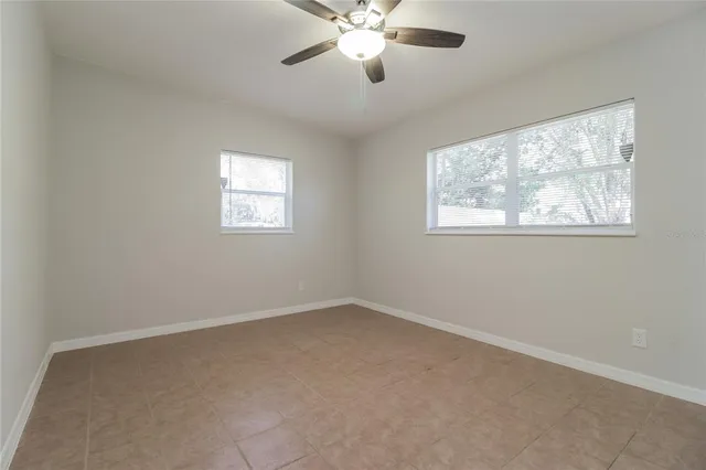 an empty room with windows and fan