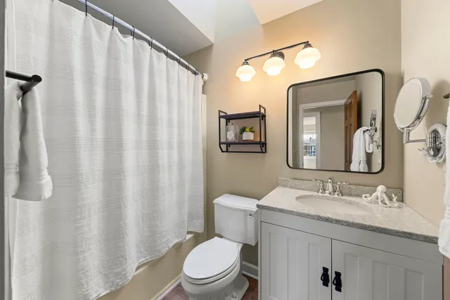 a bathroom with a granite countertop sink toilet and mirror