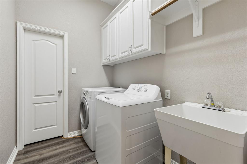 317 Singing Quail Trail Haslet, TX 76052 - Photo 24 of 32 Laundry area featuring wood-finish flooring, white cabinetry, and a utility sink