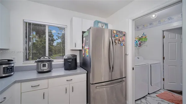 a kitchen with a sink dishwasher and white cabinets with wooden floor