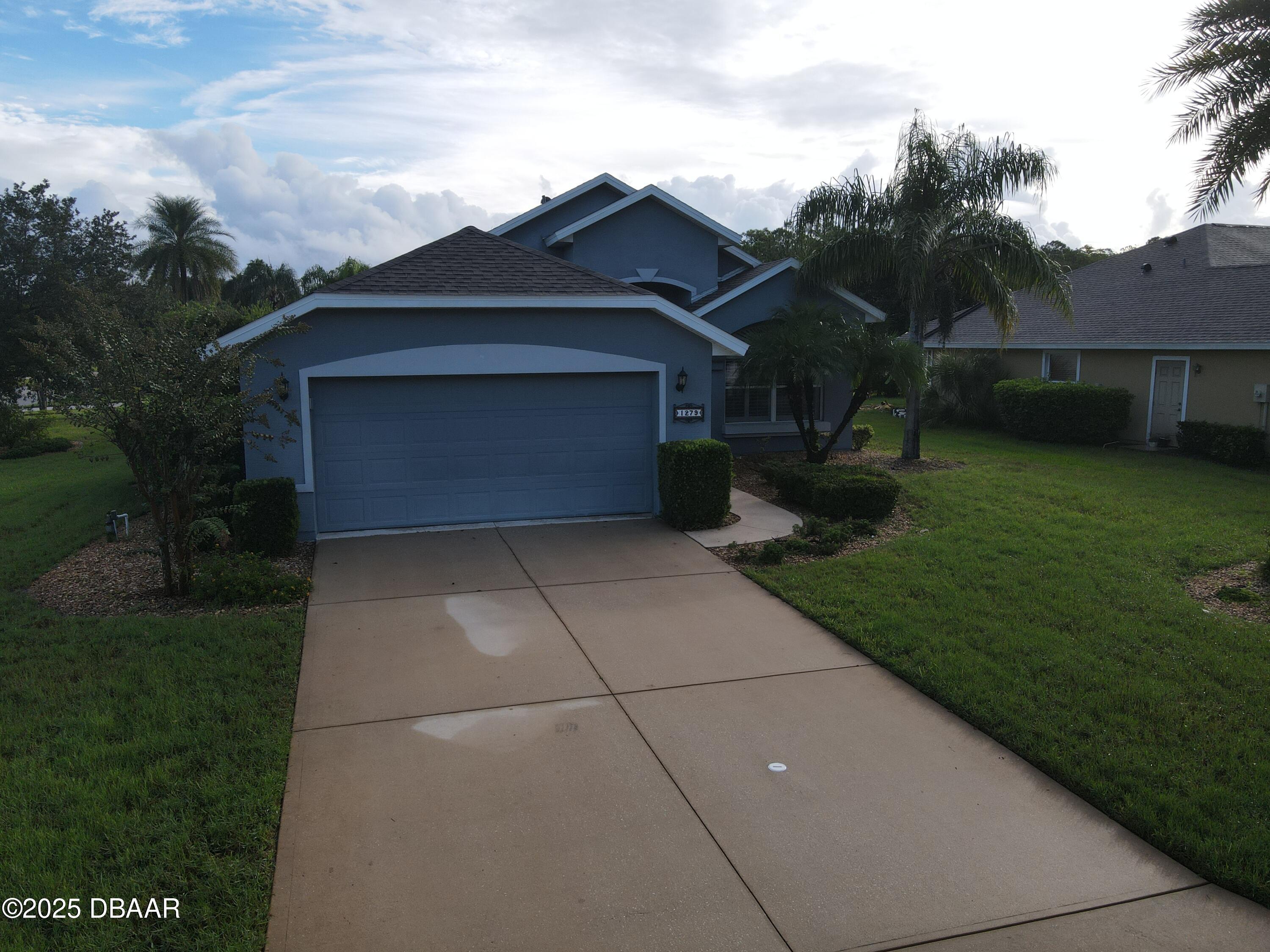 1279 Royal Pointe Lane Ormond Beach, FL 32174 - Photo 1 of 24 a front view of a house with a yard and garage