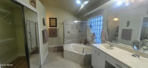 a bathroom with a tub sink double vanity granite tub shower and mirror