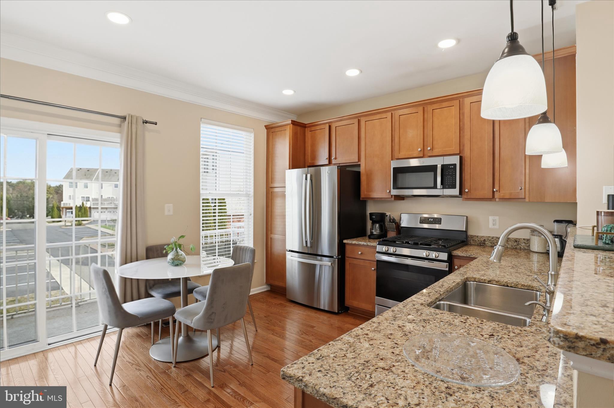 25114 Monteith Terrace Chantilly, VA 20152 - Photo 12 of 46 a kitchen with stainless steel appliances granite countertop a stove top oven a sink dishwasher a dining table and chairs with wooden floor