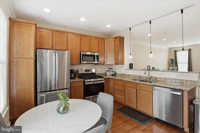 a kitchen with stainless steel appliances granite countertop a stove a sink a microwave a refrigerator a dining table and chairs