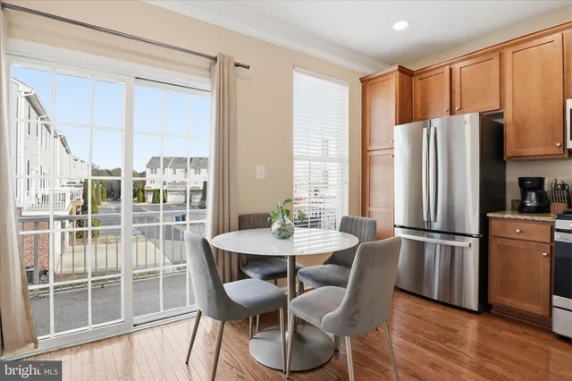 a kitchen with stainless steel appliances a dining table chairs refrigerator and cabinets