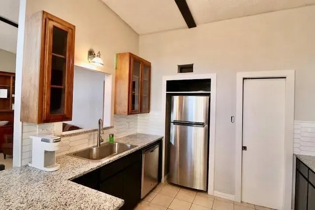 a kitchen with stainless steel appliances granite countertop a refrigerator a sink and white cabinets