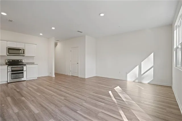 a view of empty room with wooden floor and electronic appliances