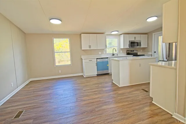 a kitchen with stainless steel appliances granite countertop a stove top oven a sink dishwasher and a refrigerator with wooden floor