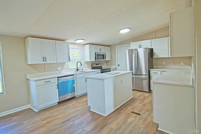 a kitchen with a refrigerator a sink and dishwasher with wooden floors