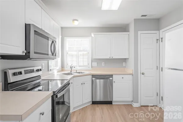 a kitchen with a sink cabinets stainless steel appliances and a window