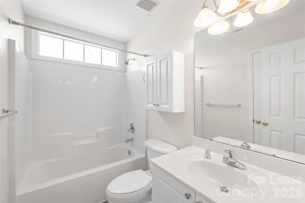 a bathroom with a bathtub shower sink vanity mirror and toilet