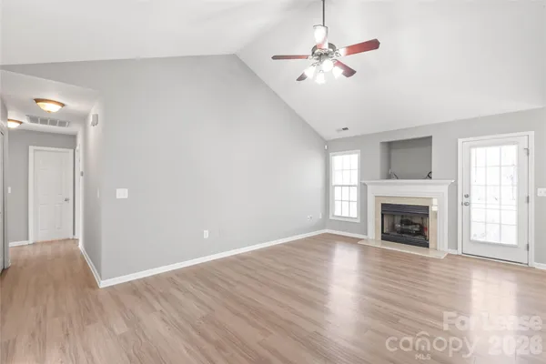 an empty room with fan fireplace and wooden floor