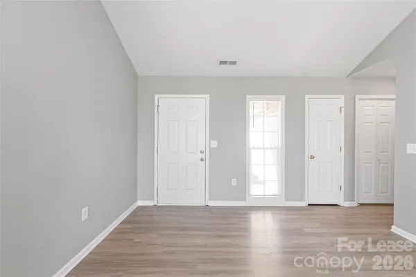 a view of an empty room with wooden floor and window