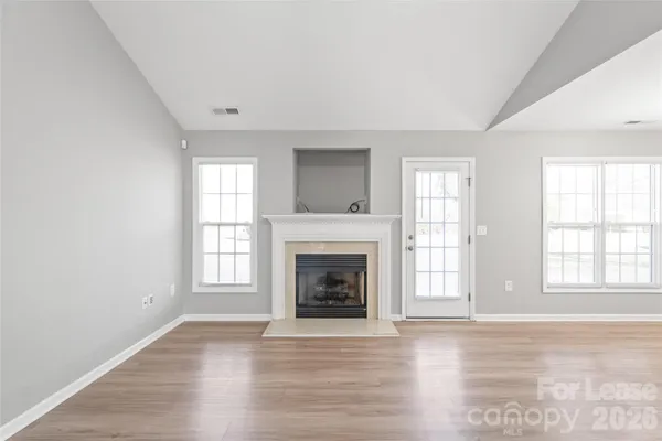 an empty room with windows and fireplace