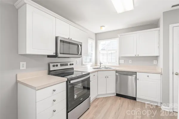 a kitchen with cabinets stainless steel appliances a sink and wooden floor