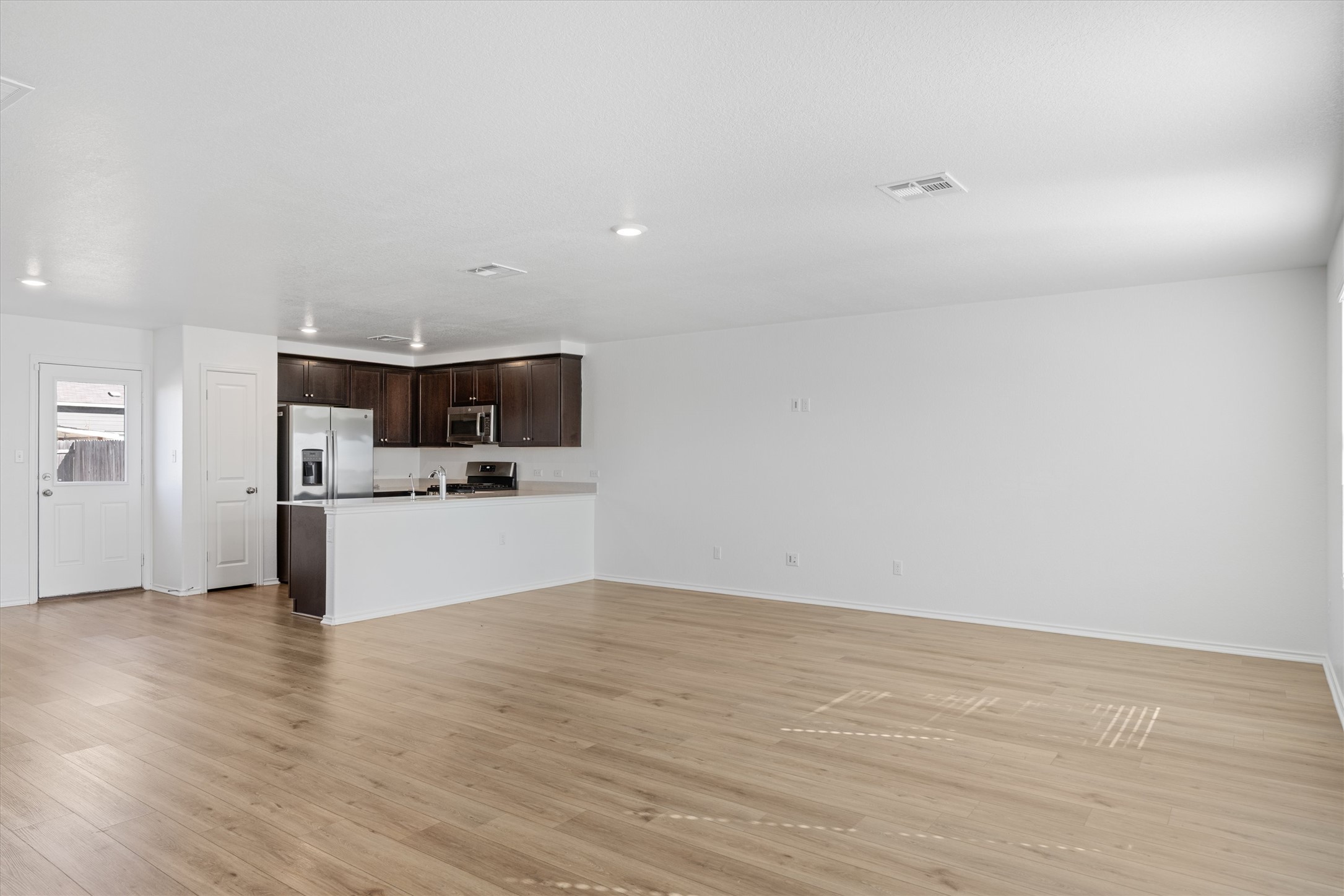 13520 Knights Branch Drive Elgin, TX 78621 - Photo 3 of 20 Unfurnished living room featuring wood-style vinyl flooring and recessed lighting