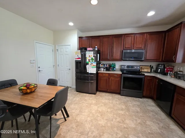 a kitchen with stainless steel appliances granite countertop a stove refrigerator a sink dishwasher and wooden cabinets with wooden floor