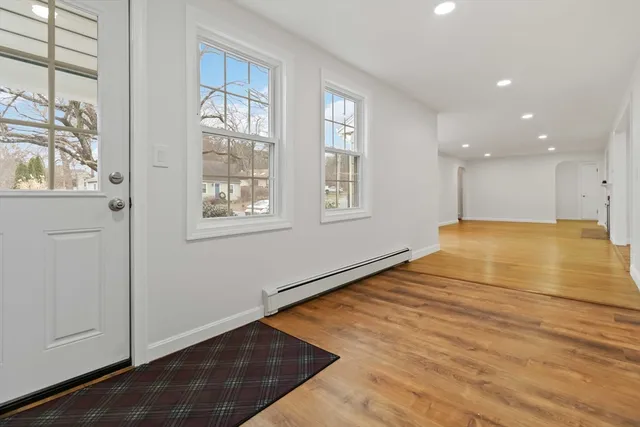 a view of an empty room with window and wooden floor