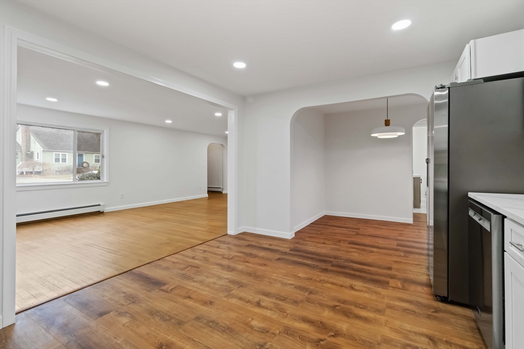 58 Cutler Drive Framingham, MA 01702 - Photo 10 of 36 a view of an empty room with wooden floor and a kitchen