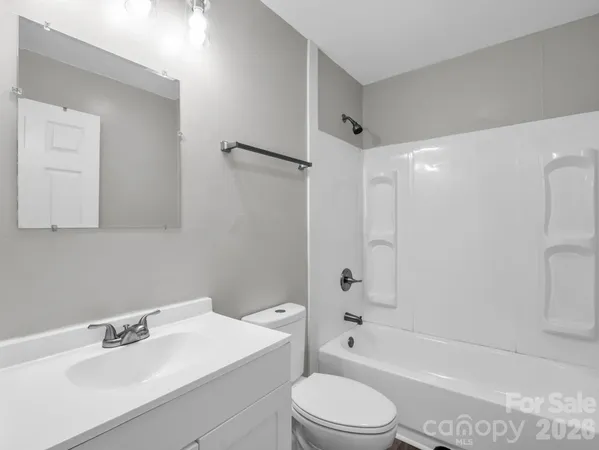 a bathroom with a bathtub shower sink vanity mirror and toilet