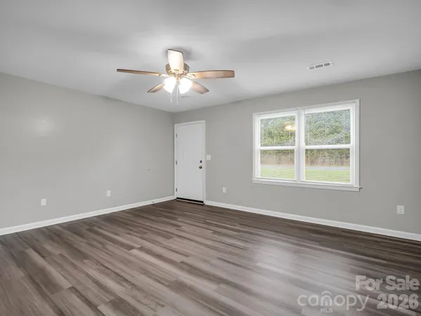 a view of an empty room with a window and wooden floor