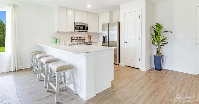 a kitchen with stainless steel appliances a refrigerator a stove a sink and a dining table with wooden floor