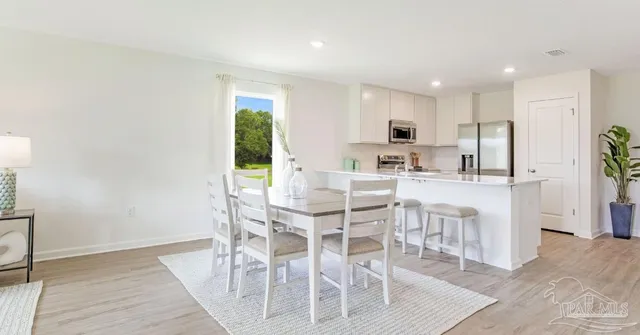 a kitchen with stainless steel appliances kitchen island granite countertop a dining table chairs and granite counter tops