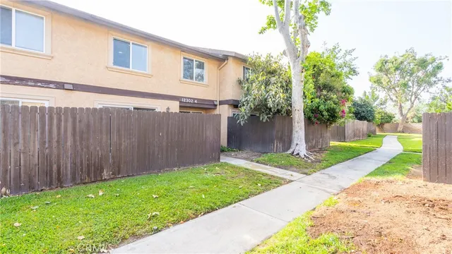 a view of a house with a small yard and a large tree
