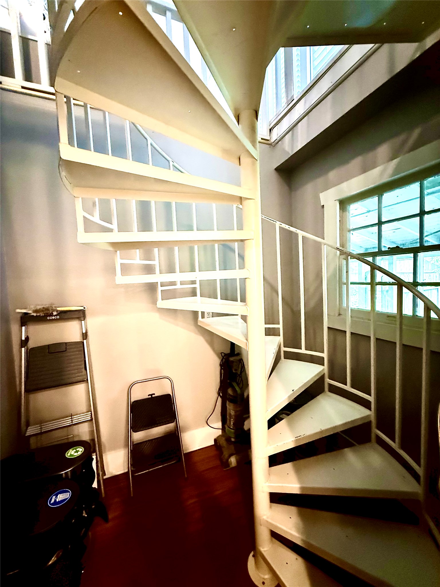 423 South Main Street Lockhart, TX 78644 - Photo 14 of 26 White spiral staircase featuring a metal railing and solid treads, complemented by dark wood-finish flooring and windows with intricate muntins