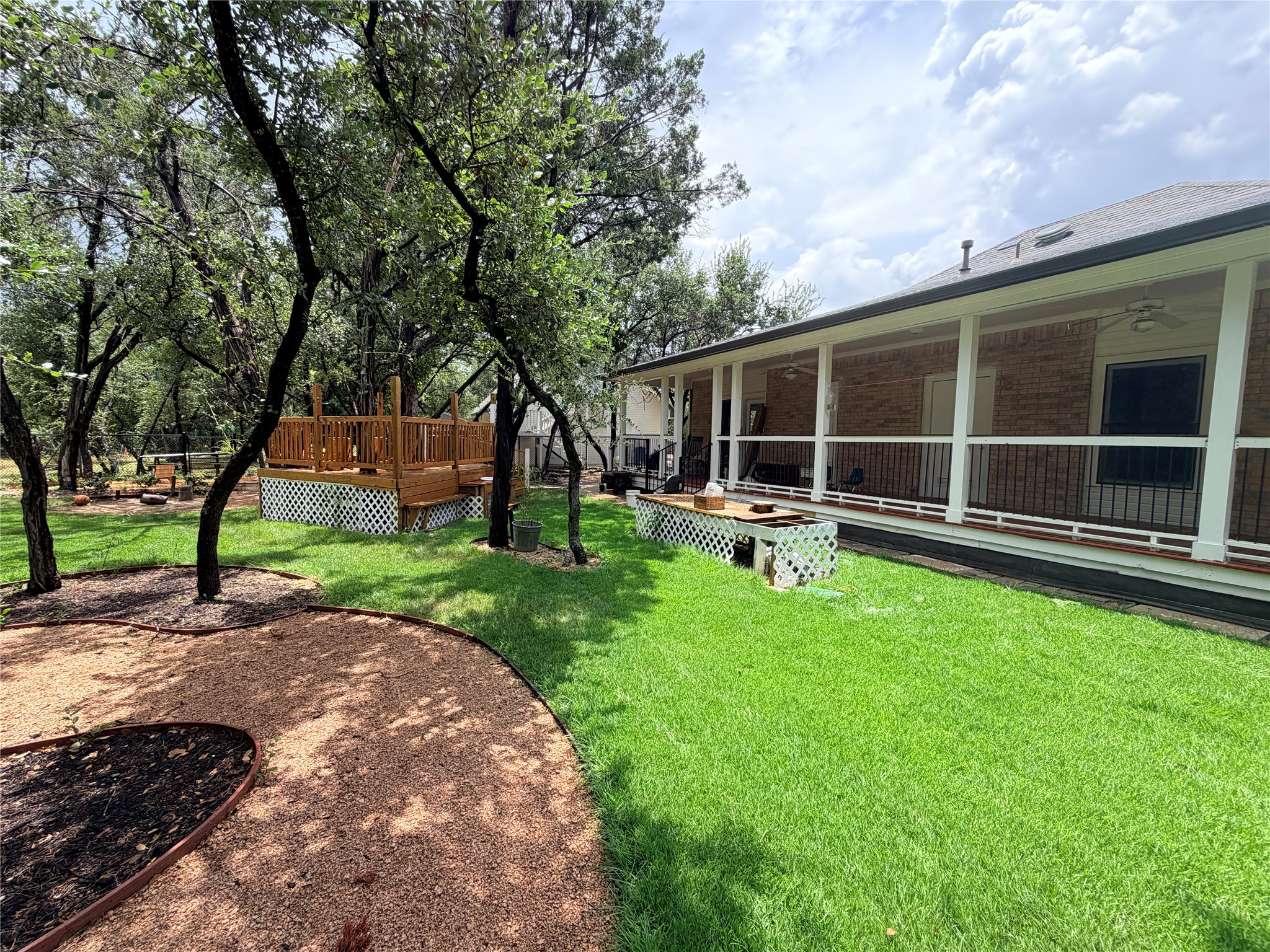 7130 Ranch 2338 Road Georgetown, TX 78633 - Photo 6 of 35 Mature trees shade a spacious lawn featuring a multi-level wooden deck and covered porch.