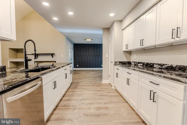 a large kitchen with stainless steel appliances granite countertop a stove top oven a sink dishwasher and a refrigerator with wooden cabinets