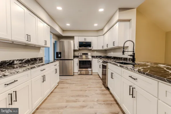 a large white kitchen with kitchen island a sink a stove a refrigerator and white cabinets