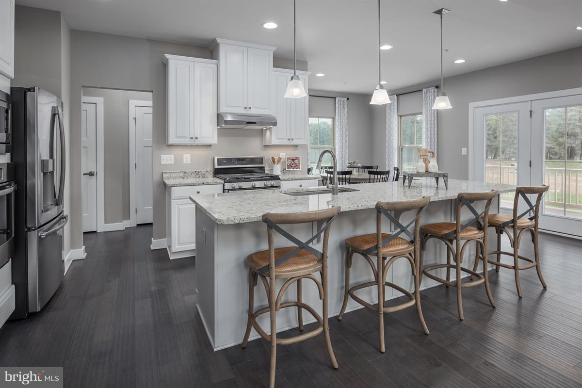 7641 Deepnotch Way Hanover, MD 21076 - Photo 3 of 25 a kitchen with stainless steel appliances a dining table chairs stove refrigerator and cabinets