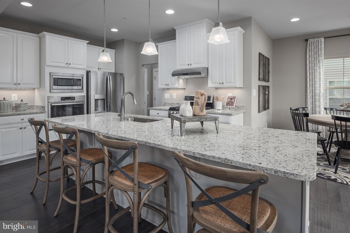 7641 Deepnotch Way Hanover, MD 21076 - Photo 4 of 25 a kitchen with kitchen island granite countertop a table chairs sink and microwave