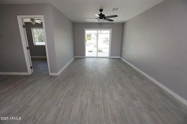 an empty room with wooden floor and windows