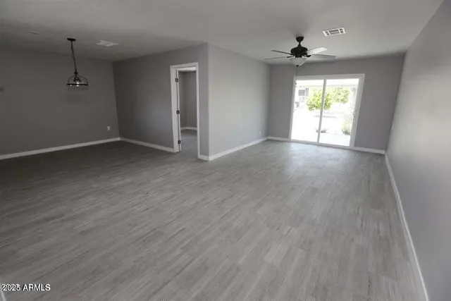 an empty room with wooden floor and windows