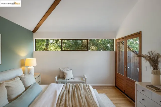 a view of a hallway with wooden floor and a bathroom
