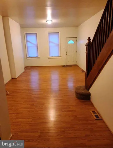 a view of an empty room with wooden floor and stairs
