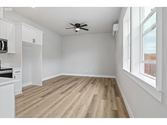 a view of an empty room with wooden floor and a window