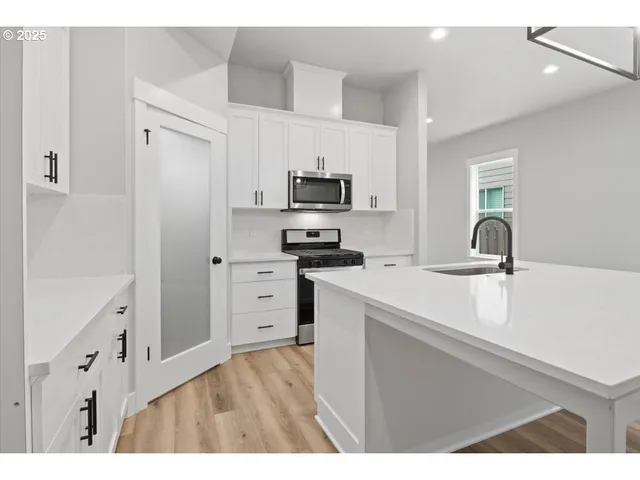 a kitchen with stainless steel appliances a stove a microwave and white cabinets
