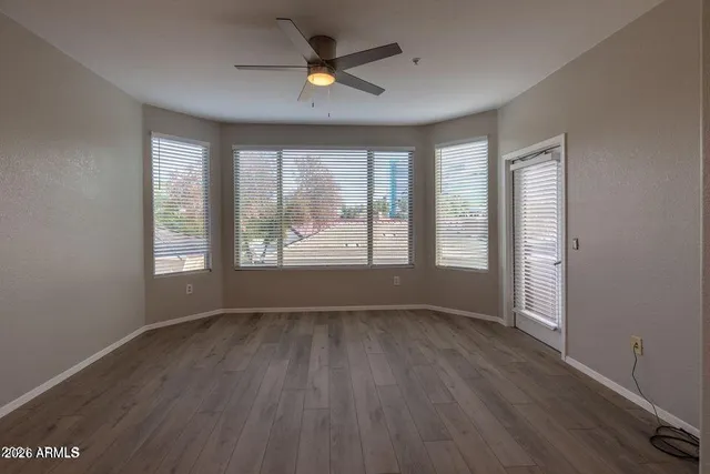 a view of an empty room with a window and wooden floor