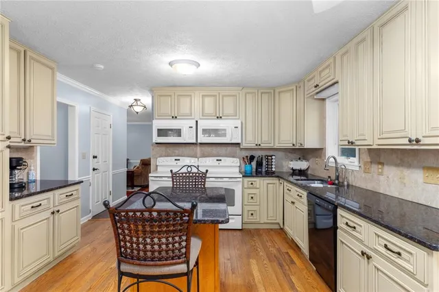 a view of a dining room and livingroom with furniture wooden floor a rug a potted plant and a chandelier