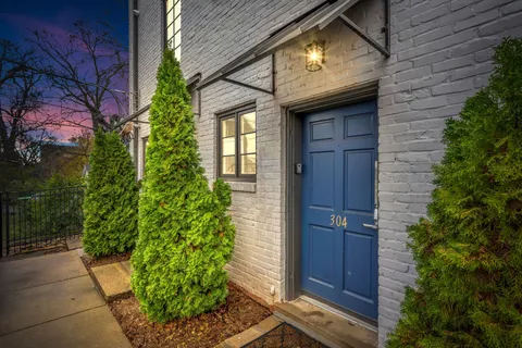 a brick house with a large window and potted plants