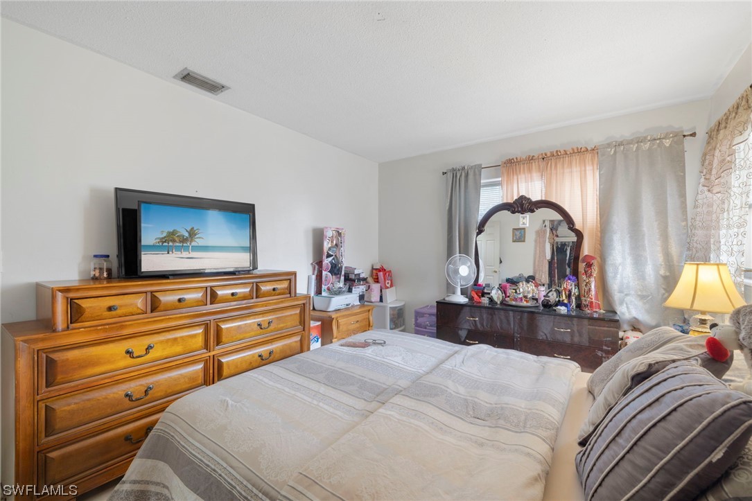 16 Massachusetts Road Lehigh Acres, FL 33936 - Photo 17 of 20 a bedroom with bed and a chandelier