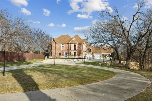 a view of a white house with a big yard and large trees