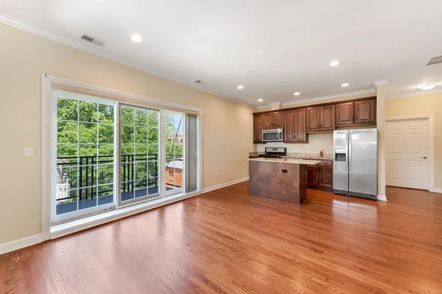 a view of kitchen with kitchen island wooden floor and refrigerator