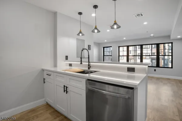 a kitchen with a sink and dishwasher with wooden floor
