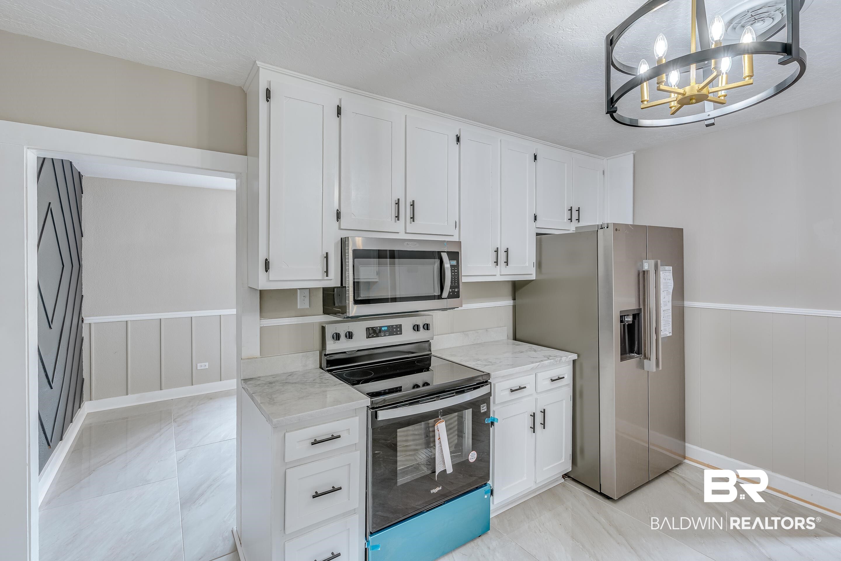 8001 16th Street Irvington, AL 36544 - Photo 14 of 35 Kitchen featuring a wainscoted wall, stainless steel appliances, white cabinets, a textured ceiling, and a chandelier