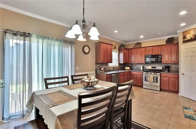 a kitchen with a refrigerator a stove a sink dishwasher with a dining table and chairs